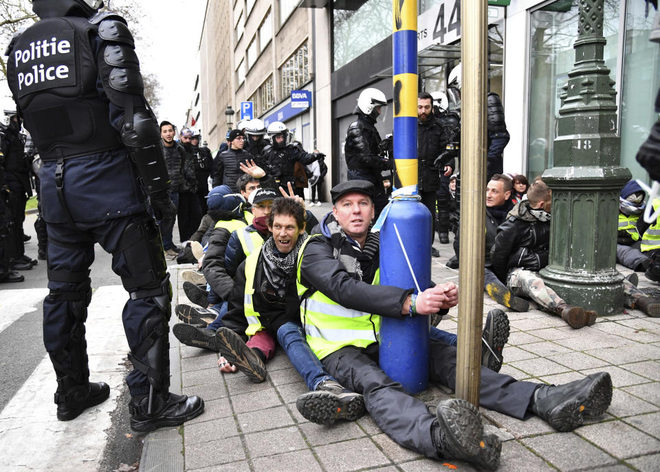 A police stands by as protestors are detained during a demonstration in Brussels, Saturday, Dec. 8, 2018. Hundreds of police officers are being mobilized in Brussels Saturday, where yellow vest protesters last week clashed with police and torched two police vehicles. More than 70 people were detained. (AP Photo/Geert Vanden Wijngaert)