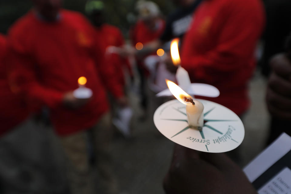 People hold candles during a candlelight vigil outside city hall for deceased and injured workers from the Hard Rock Hotel construction collapse Sat., Oct. 12, in New Orleans, on Thursday, Oct. 17, 2019. The vigil was organized by various area labor groups. (AP Photo/Gerald Herbert)