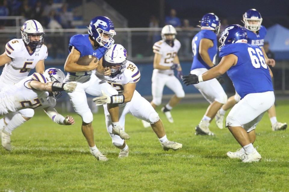 Nevada's Austin Waldera (21) and Jackson Burlage (32) work to bring down a Perry player on Friday, Sept. 22, 2023, at Dewey Field in Perry.