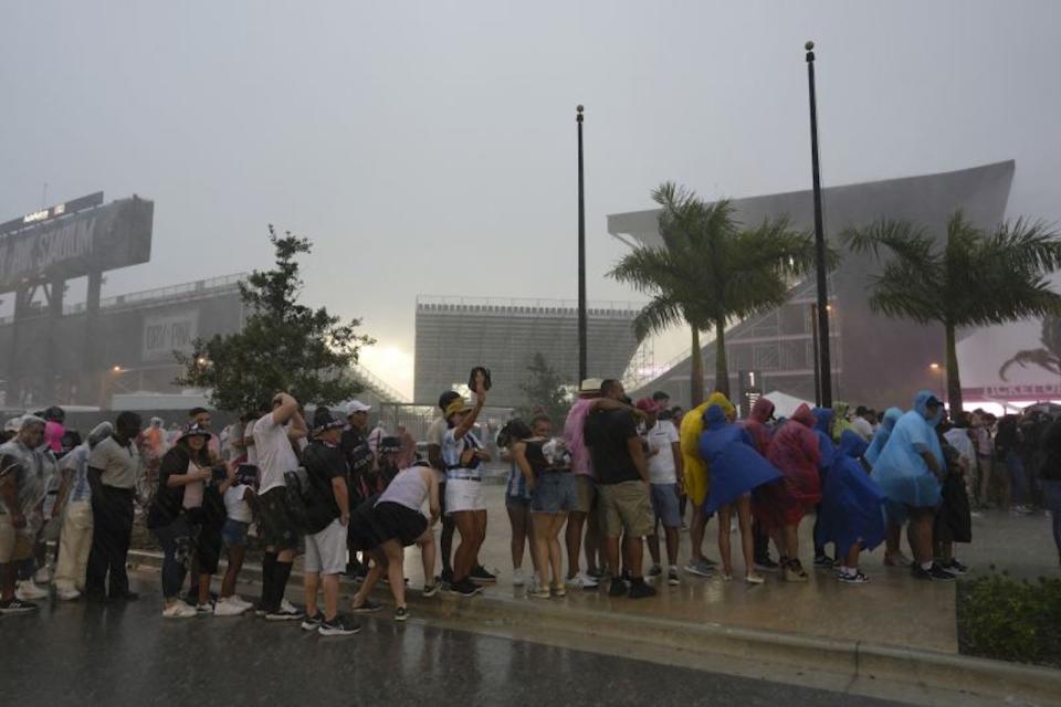 Aficionados esperan en fila durante un aguacero en el estadio de Inter Miami. (Crédito: Rebecca Blackwell/AP)