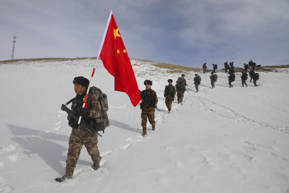 Soldiers march with a Chinese flag during field exercises in the snow near the Kunjerab Pass bordering Pakistan in Taxkorgan in northwest China's Xinjiang Uyhgur Autonomous Region on Jan. 6, 2021. China appointed on Friday, Aug. 6, 2021 a new military commander in restive Xinjiang where authorities have locked up more than a million members of Muslim minorities in what they call a bid to curb terrorism and radicalism. (Chinatopix via AP)