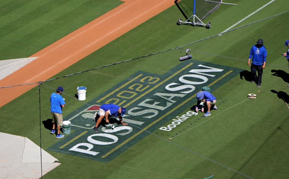 Grounds crew workers prepare the field at Dodger Stadium for the NLDS.