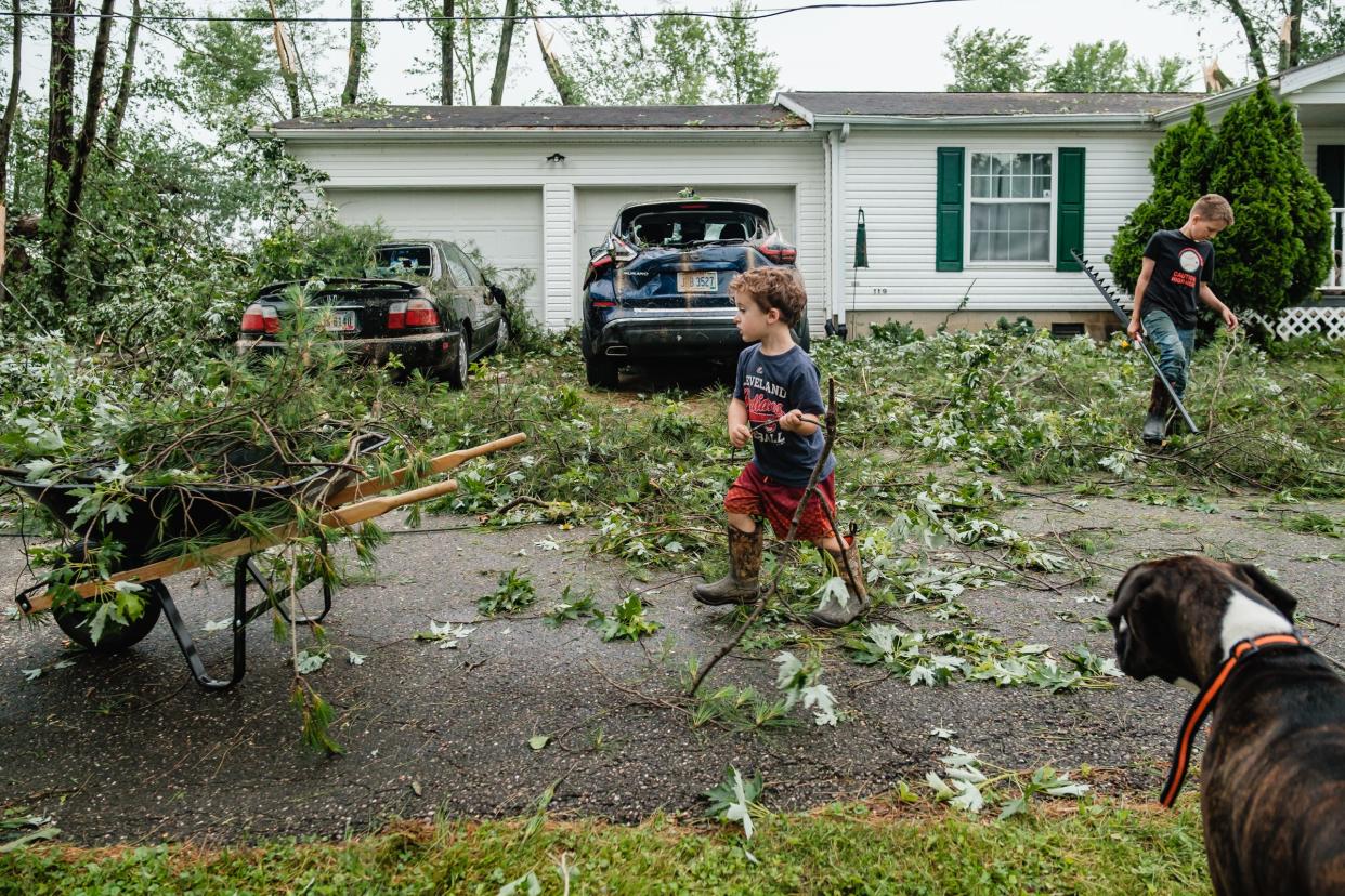 Cousins Zayden Yant, 3, and Derrik Roth, 12, help to clear brush to their grandparent's property after an overnight storm caused severe damage to the area, Tuesday, June 14 in Gnadehutten.