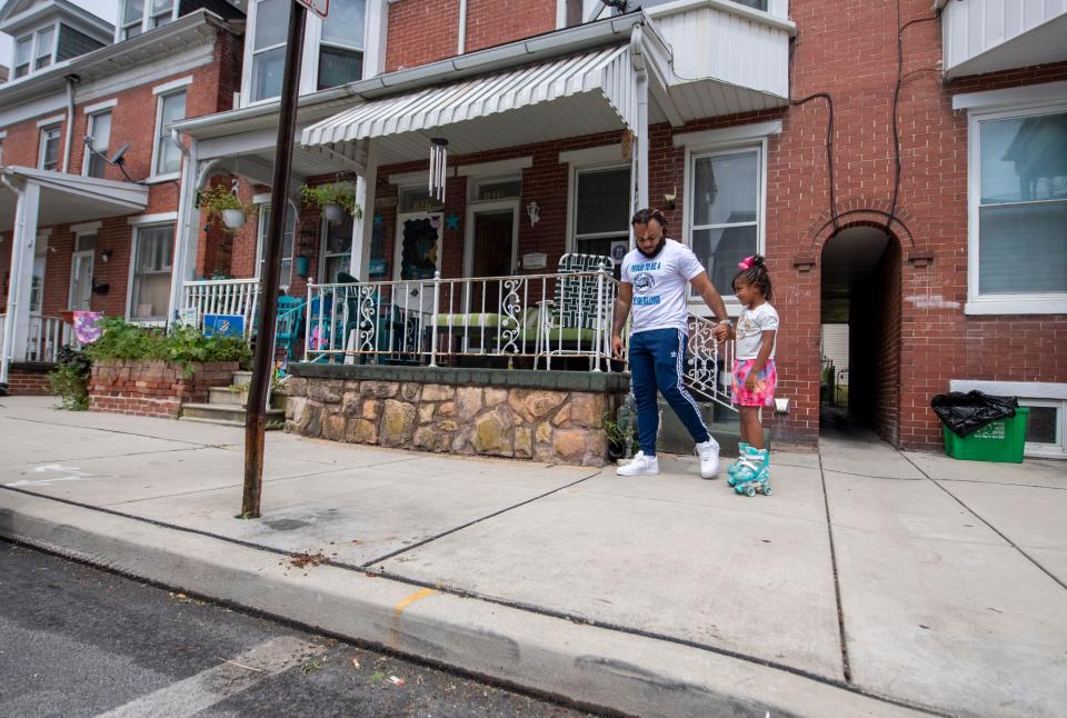 Nathan Fleming with his daughter Olivia, age 6, cross between York city and West York in front of their home. The white line in the street designates the border. Their living room couch straddles the two municipalities. 