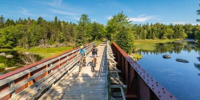 Two people cycle along a wooden bridge on the Rum Runner's Trail in Nova Scotia. Credit: Adam Cornick. (CNW Group/Trans Canada Trail)