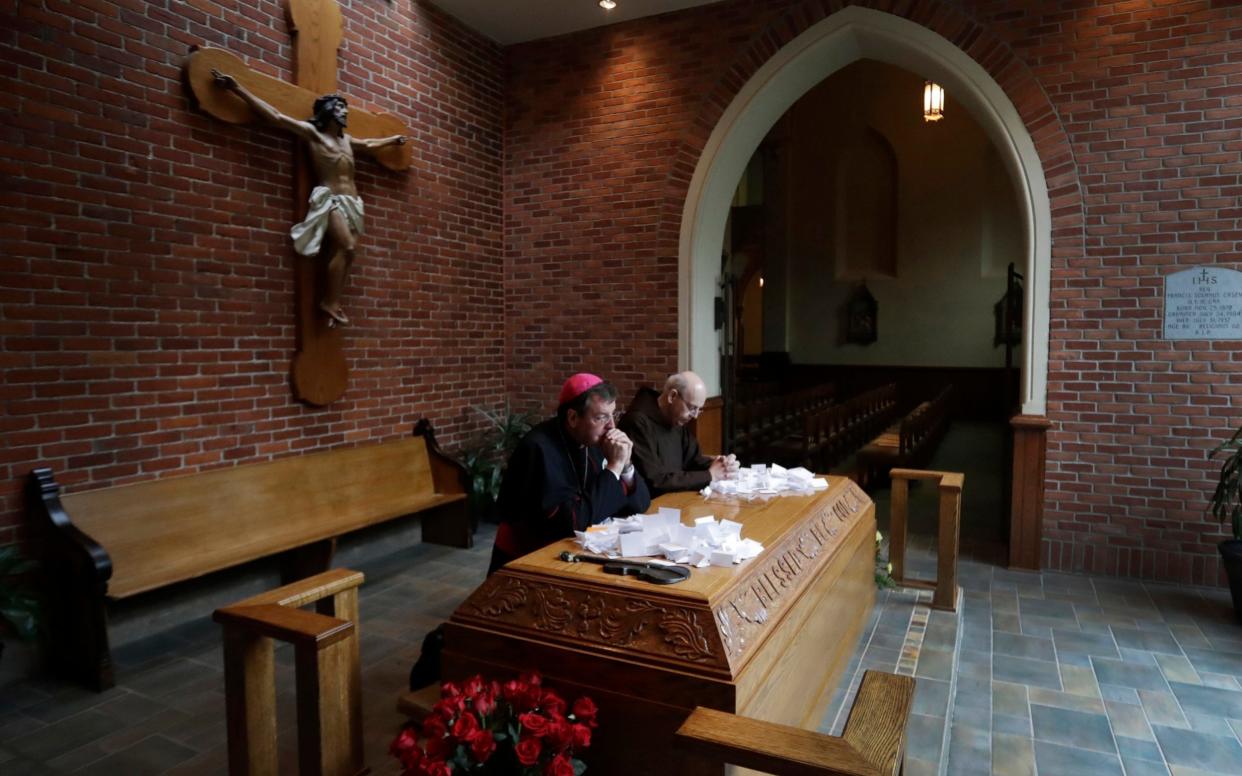 Archbishop Allen Vigneron, left, and Michael Sullivan, Provincial Minister of the Capuchin Franciscan Province of St. Joseph, pray at the tomb of Father Solanus Casey in Detroit - AP