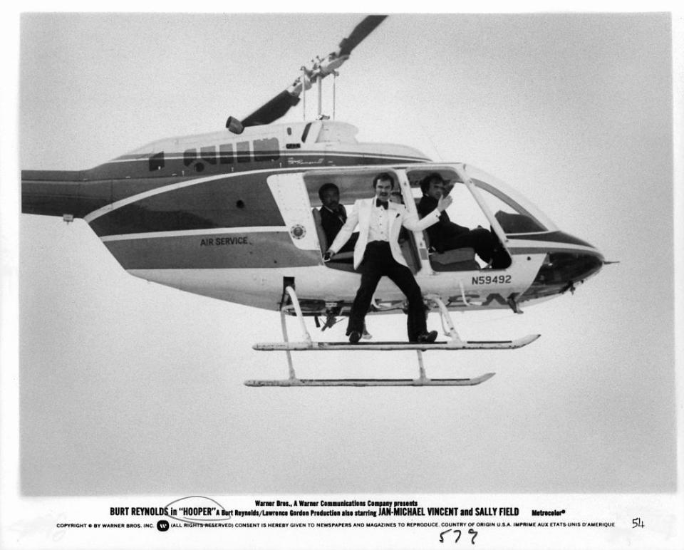 <p>Burt Reynolds shoots a daring scene on a helicopter for his movie <em>Hooper</em> in 1978. The film was the actor's follow-up to <em>Smokey and the Bandit. </em></p>