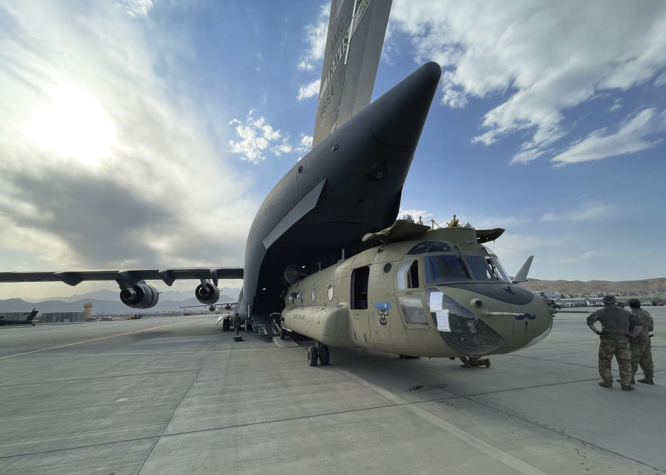 In this image provided by the Department of Defense, a CH-47 Chinook from the 82nd Combat Aviation Brigade, 82nd Airborne Division is loaded onto a U.S. Air Force C-17 Globemaster III at Hamid Karzai International Airport in Kabul, Afghanistan, Saturday, Aug, 28, 2021. (Department of Defense via AP)