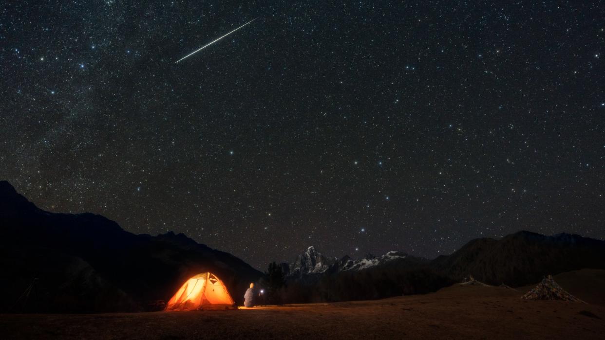  a meteor shower in the sky above a tent 