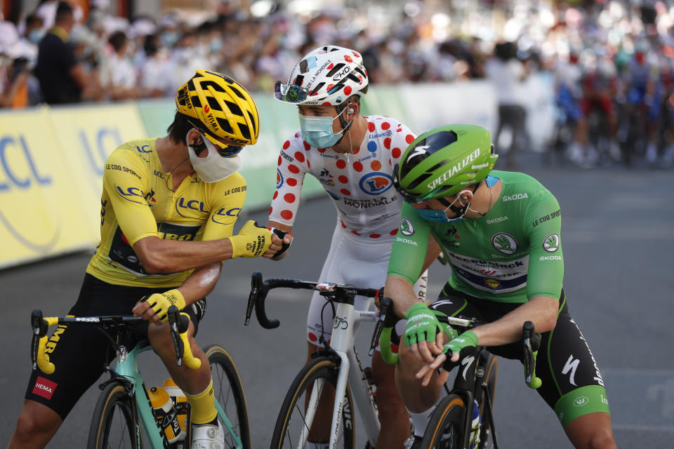 Slovenia's Primoz Roglic, wearing the yellow jersey of the overall leader speaks with Ireland's Sam Bennett, wearing the best sprinters green jersey as he gets a fist bump from France's Benoit Cosnefroy before the 14th stage of the Tour de France cycling race over 194 kilometers (120,5 miles) with start in Clermont-Ferrand and finish in Lyon, France, Saturday, Sept. 12, 2020. (AP Photo/Thibault Camus)