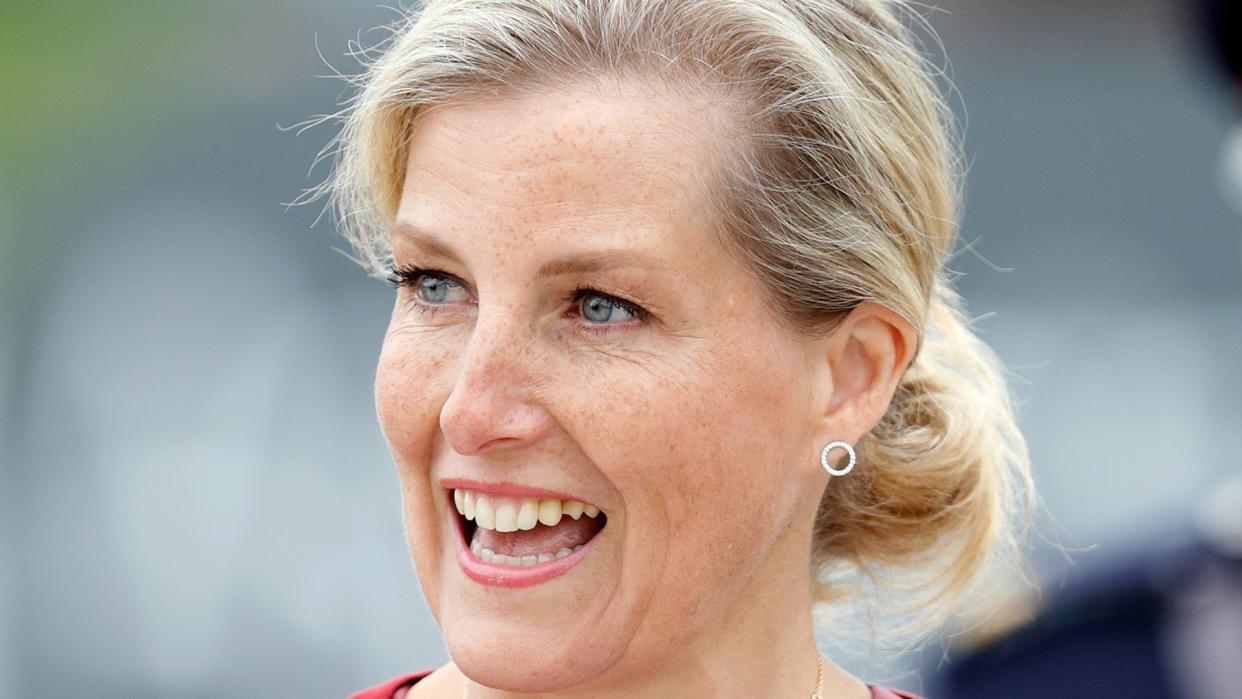 woman smiling in pink dress and red cardigan