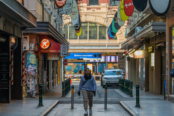 A lone man walks down Degraves street past closed cafes and restaurants in Melbourne, Australia. 