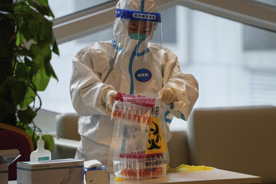 A health worker wearing a protective suit puts COVID-19 test samples into a plastic bag at a hotel used for people to stay during a period of health quarantine Sunday, March 20, 2022, in the Yanqing district of Beijing. (AP Photo/Andy Wong)