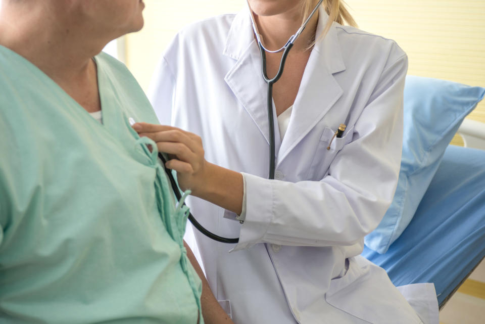 A doctor using a stethoscope to check their patient