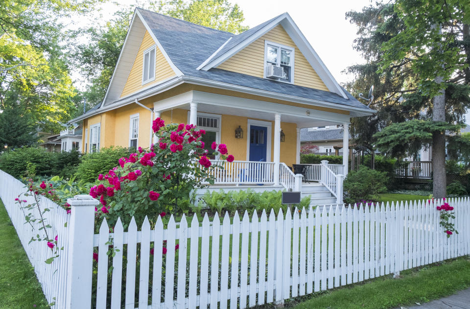 Yellow house with white picket fence.