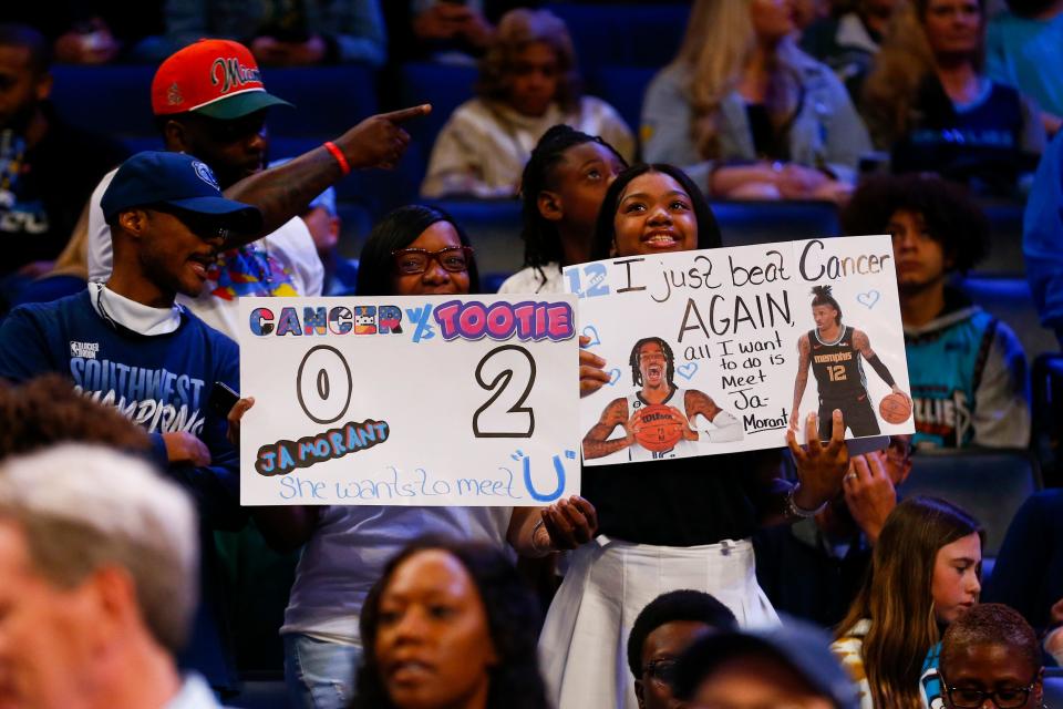 Tanisa Bradley and Tytiana Bradley, 19, from Madison, Alabama, hold up signs asking to meet Ja Morant before the start of the game between the Memphis Grizzlies and the Houston Rockets at FedExForum in Memphis, Tenn., on March 22, 2023. Tytiana Bradley found out she was cancer free and her mom surprised her with tickets to the game.