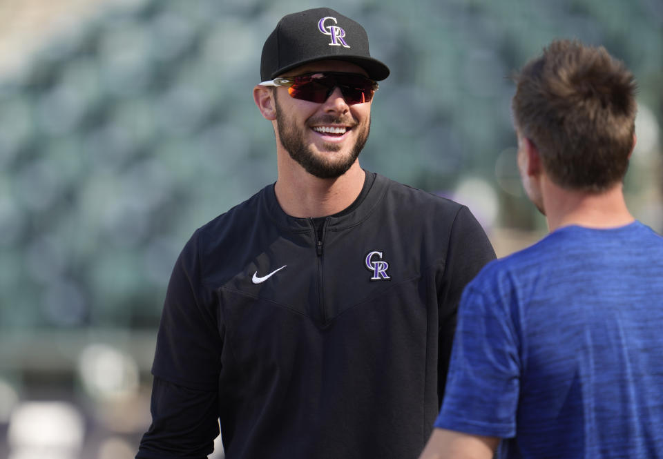 Colorado Rockies left fielder Kris Bryant, left, jokes with head athletic trainer P.J. Mainville, of the Chicago Cubs, as players warm up before a baseball game Thursday, April 14, 2022, in Denver. (AP Photo/David Zalubowski)