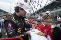 Colton Herta signs autograph during a practice session for the Indianapolis 500 auto race at Indianapolis Motor Speedway, Thursday, May 16, 2024, in Indianapolis. (AP Photo/Darron Cummings)