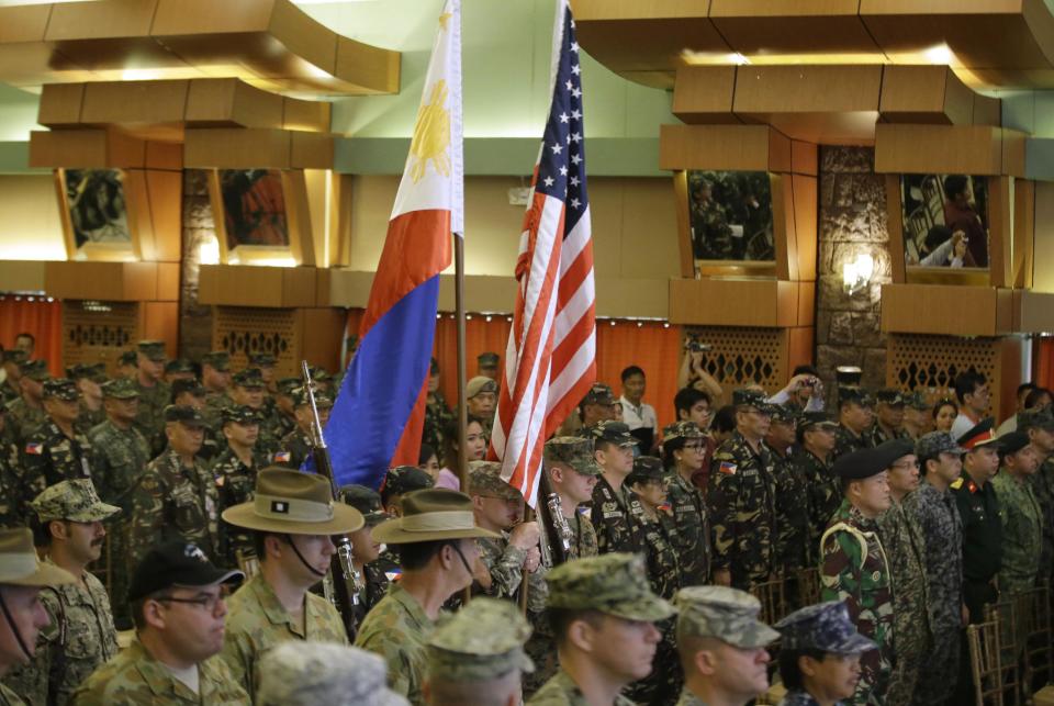 Military officers from the U.S., Philippines, Asutralia and others stand at attention during the entrance of the colors to signal the opening ceremony for the joint U.S.-Philippines military exercise dubbed Balikatan 2014 Monday, May 5, 2014 at the Armed Forces of the Philippines headquarters at suburban Quezon city, northeast of Manila, Philippines. More than 5,000 U.S. and Filipino troops began two weeks of military exercises Monday to prepare to jointly deal with any potential crisis in the Philippines, which is prone to natural disasters and has been locked in a dangerous territorial standoff with China.(AP Photo/Bullit Marquez)