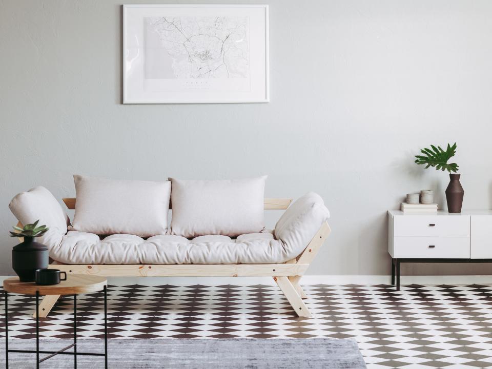 A futon with white cushions on a black and white rug