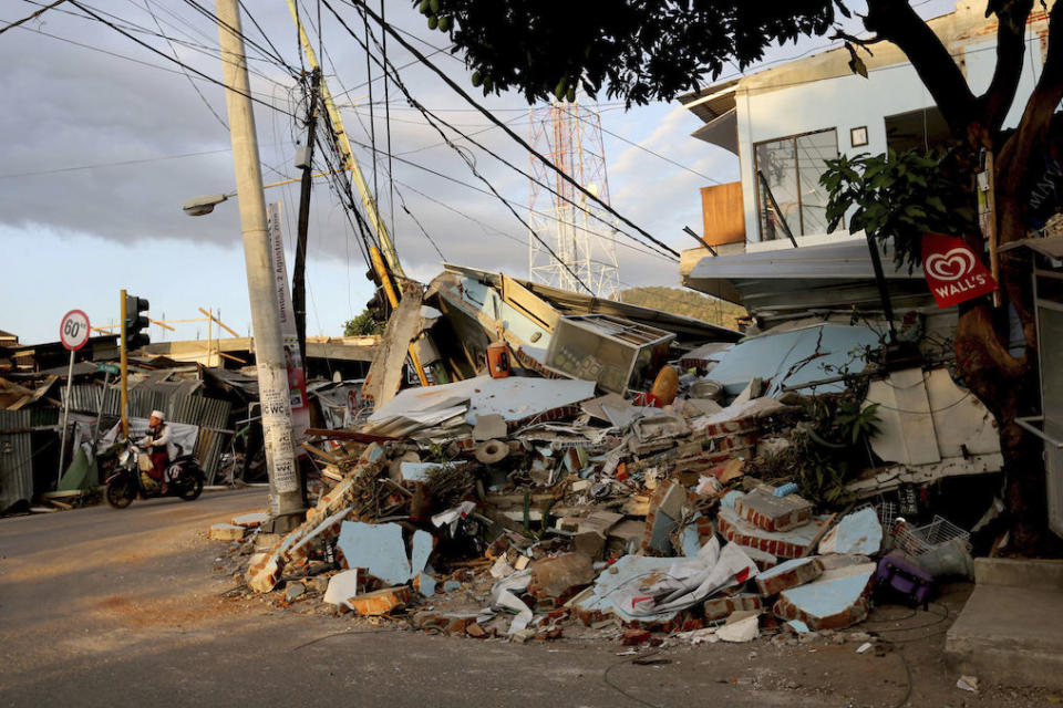 A motorist rides past a house heavily damaged by an earthquake in North Lombok, Indonesia (Picture: AP)