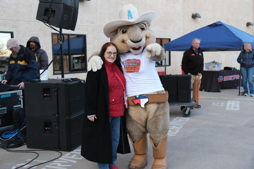 Beth Duke, executive director of Center City, shares a moment with Ruckus of the Amarillo Sod Poodles Saturday morning at the Center City Mural Run in downtown Amarillo.