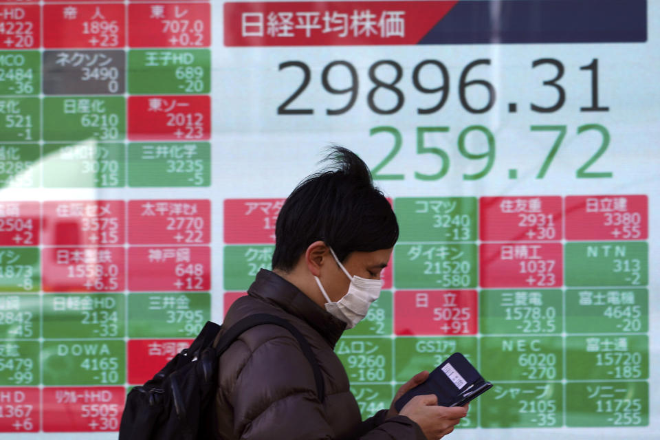 A man wearing a protective mask walks in front of an electronic stock board showing Japan's Nikkei 225 index at a securities firm Wednesday, Feb. 24, 2021, in Tokyo. Shares fell in Asia on Wednesday as investors weighed the possibility that inflation might prompt central banks to adjust their ultra-low interest rate policies. (AP Photo/Eugene Hoshiko)