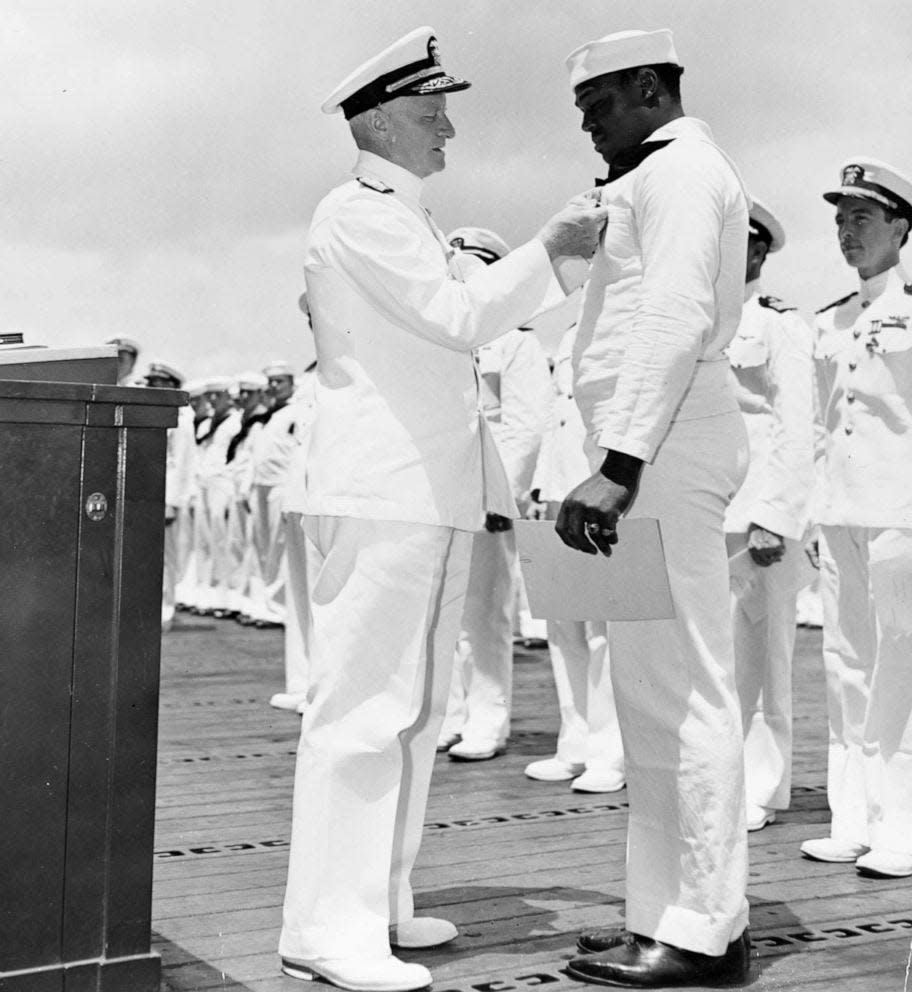 Adm. Chester Nimitz awards the Navy Cross medal to Mess Attendant Second Class Doris Miller for his actions aboard the battleship USS West Virginia (BB-48) during the Dec. 7, 1941 Japanese attack on Pearl Harbor. The award was presented to Miller aboard the aircraft.