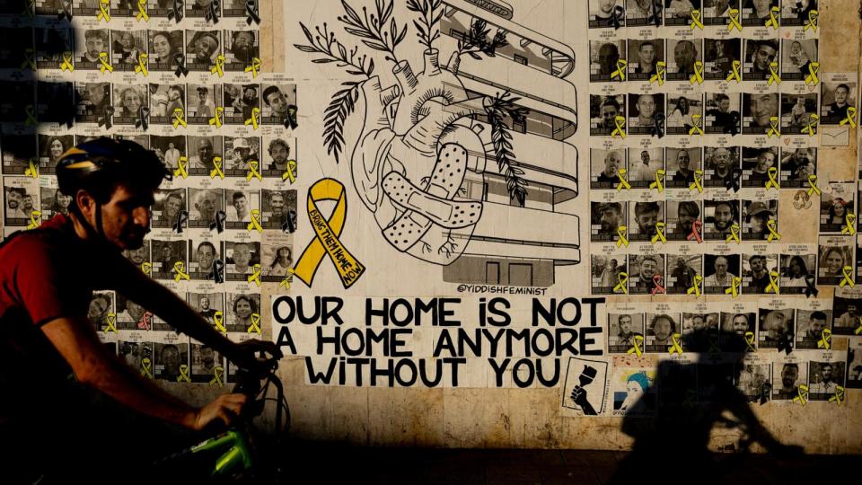 PHOTO: A man passes by a wall covered with photos of hostages held in the Gaza Strip as he rides a bicycle, August 15, 2024, in Tel Aviv, Israel. (Amir Levy/Getty Images)