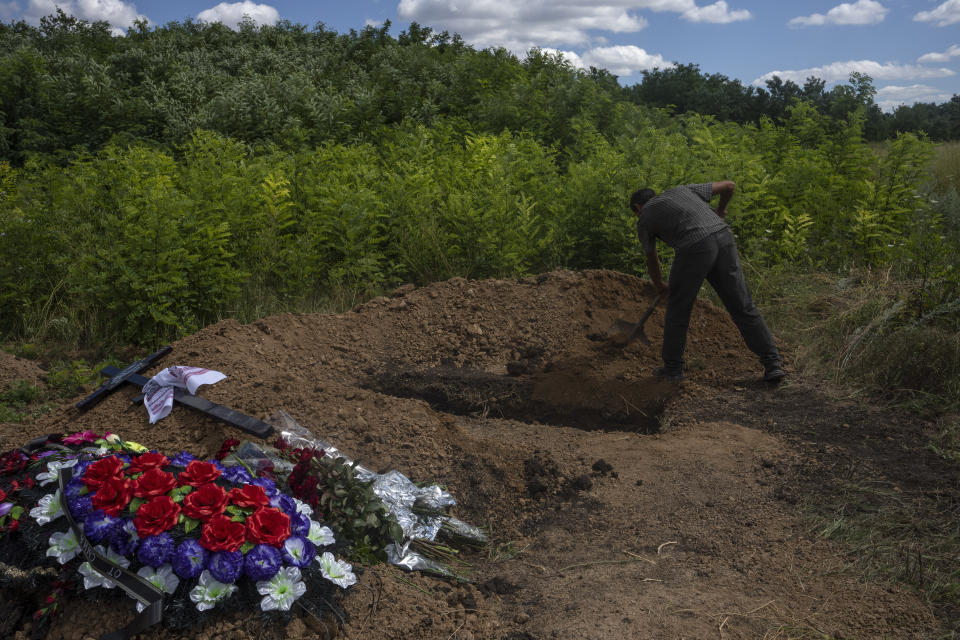 A gravedigger covers the coffin of 35-year-old Anna Protsenko, who was killed in a Russian rocket attack, after her funeral procession, on the outskirts of Pokrovsk, eastern Ukraine, Monday, July 18, 2022. (AP Photo/Nariman El-Mofty)