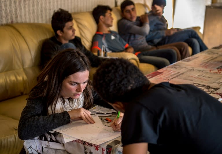 A volunteer gives a French lesson to a migrant in a makeshift restaurant at the so-called 'Jungle' camp in the French northern port city of Calais