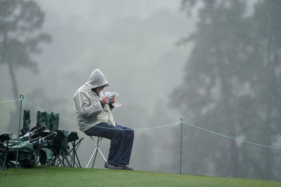 FILE - Apr 8, 2023; Augusta, Georgia, USA; A patron sits in the rain while watching the action on the 18th green during the third round of The Masters golf tournament. Mandatory Credit: Danielle Parhizkaran-USA TODAY Network
