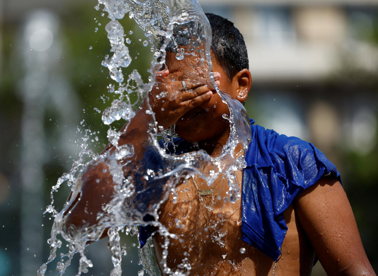 A boy splashes himself in a fountain amid the heat wave.