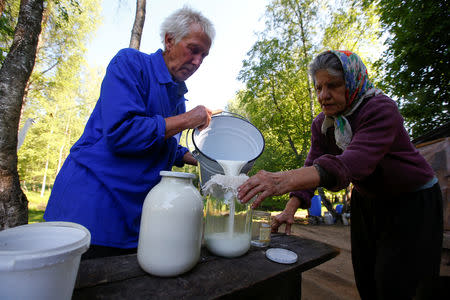 Tamara and Yuri Baikov, both 69, pour goats' milk at their small farm situated in a forest near the village of Yukhovichi, Belarus, May 25, 2018. REUTERS/Vasily Fedosenko