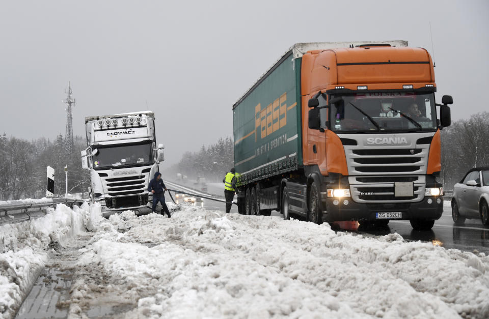 Truck drivers help each other after being trapped by heavy snowfall on the Autobahn A8 near Holzkirchen, southern Germany, Monday, Jan. 7, 2019. (Tobias Hase/dpa via AP)