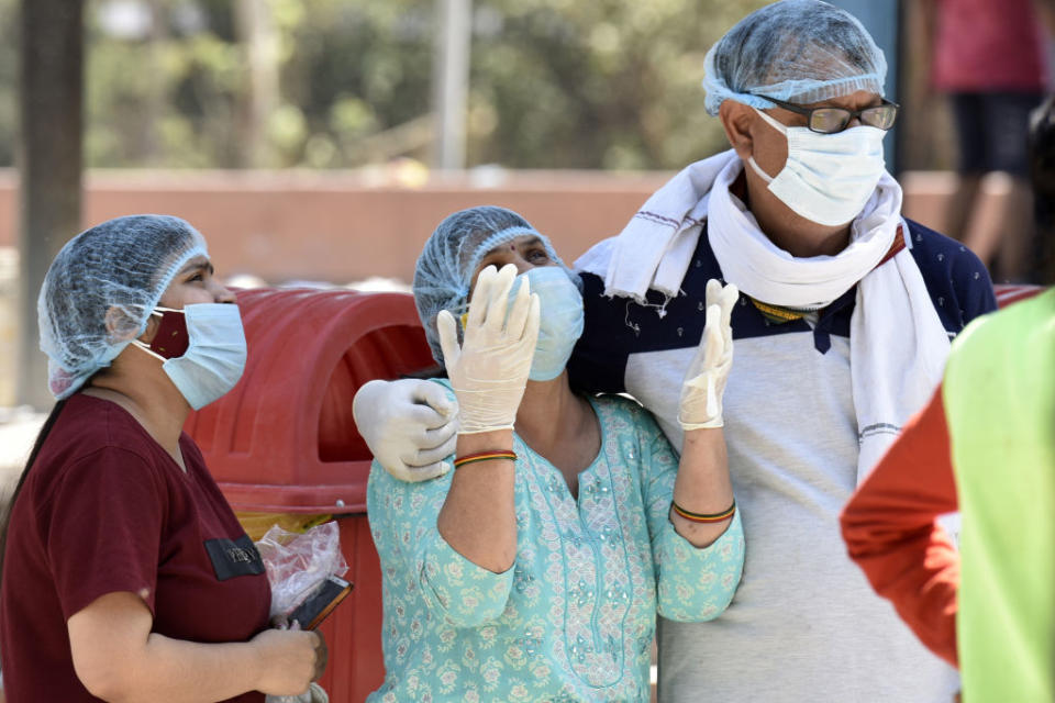 Relatives of a person who died of Covid-19 at the crematorium, at Sector 94,  in Noida, India. 