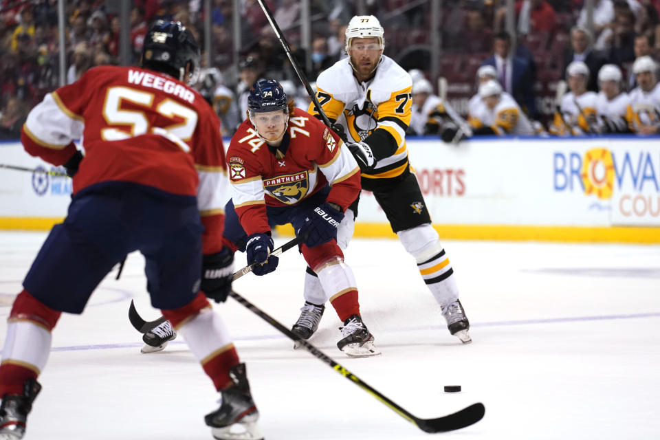 Florida Panthers right wing Owen Tippett (74) passes the puck as Pittsburgh Penguins center Jeff Carter (77) defends during the first period of an NHL hockey game Thursday, Oct. 14, 2021, in Sunrise, Fla. (AP Photo/Lynne Sladky)