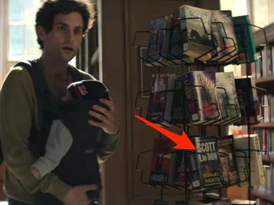 Joe in the library with his baby with an arrow pointing to the Scott Landon books