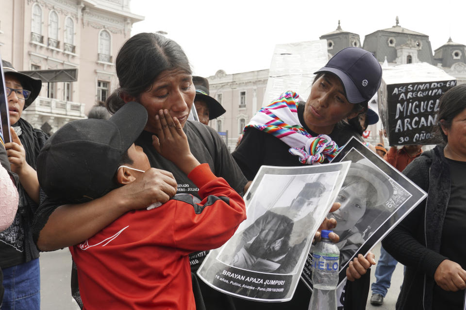 Frank Apaza consuela a su madre Asunta Jumpiri, quien sostiene un cartel de su difunto hijo Brayan Apaza, durante una protesta exigiendo que la presidenta Dina Boluarte pida elecciones inmediatas y justicia para los asesinados en las protestas tras la destitución de su predecesor Pedro Castillo, en Lima, Perú, el sábado 29 de julio de 2023. El hijo de 15 años de Jumpiri fue asesinado a tiros durante las protestas antigubernamentales que sacudieron Perú a principios de 2023. (Foto AP/Franklin Briceño)