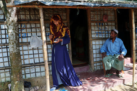 Formin Akter, a Rohingya refugee girl, uses her mobile phone as her father Mohammad Hossain watches before she departs for Chittagong to attend school at the Asian University for Women, in Cox's Bazar, Bangladesh, August 24, 2018. Picture taken August 24, 2018. REUTERS/Mohammad Ponir Hossain