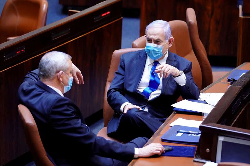 FILE PHOTO: Israeli Prime Minister Benjamin Netanyahu and Benny Gantz, wear face masks as they talk during a swearing in ceremony of the new government, at Israel's parliament, in Jerusalem