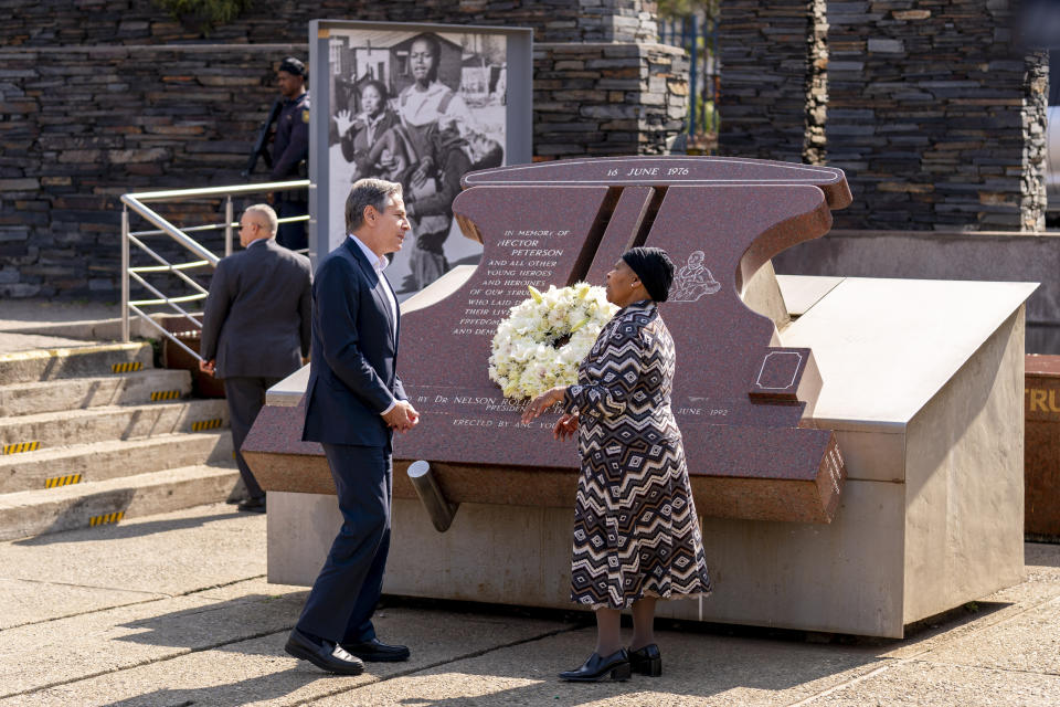 Secretary of State Antony Blinken and Antoinette Sithole, the sister of the late Hector Pieterson, lay a wreath at the Hector Pieterson Memorial in Soweto, South Africa, Sunday, Aug. 7, 2022. Peaceful child protesters were gunned down by police 30 years ago in an attack that awakened the world to the brutality of the apartheid regime. At top, is an iconic picture of Antoinette, running with mouth open in a scream alongside a friend carrying the body of her slain brother, Hector. (AP Photo/Andrew Harnik, Pool)