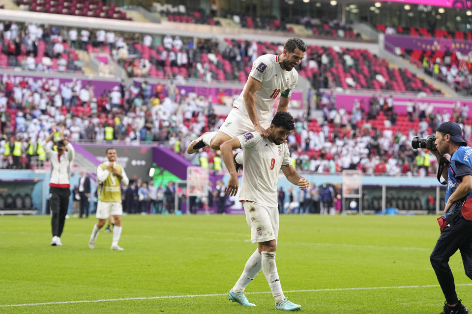 Iran's Karim Ansarifard, top, and Mehdi Taremi celebrate at the end of the World Cup group B soccer match between Wales and Iran, at the Ahmad Bin Ali Stadium in Al Rayyan , Qatar, Friday, Nov. 25, 2022. (AP Photo/Pavel Golovkin)