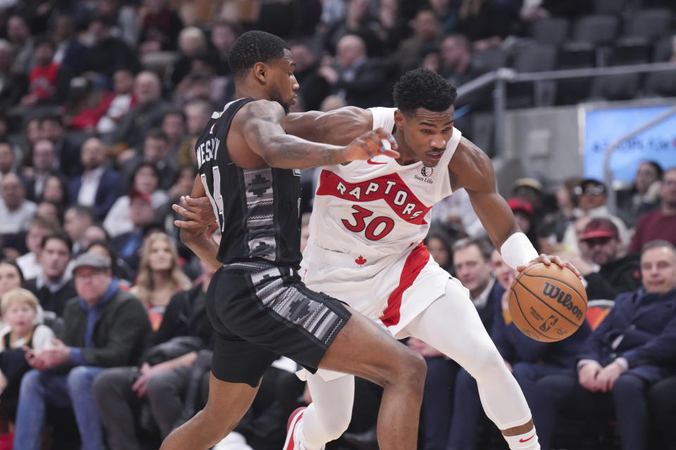 Toronto Raptors' Ochai Agbaji (30) drives past San Antonio Spurs' Blake Wesley, left, during second-half NBA basketball game action in Toronto, Monday Feb. 12, 2024. (Chris Young/The Canadian Press via AP)