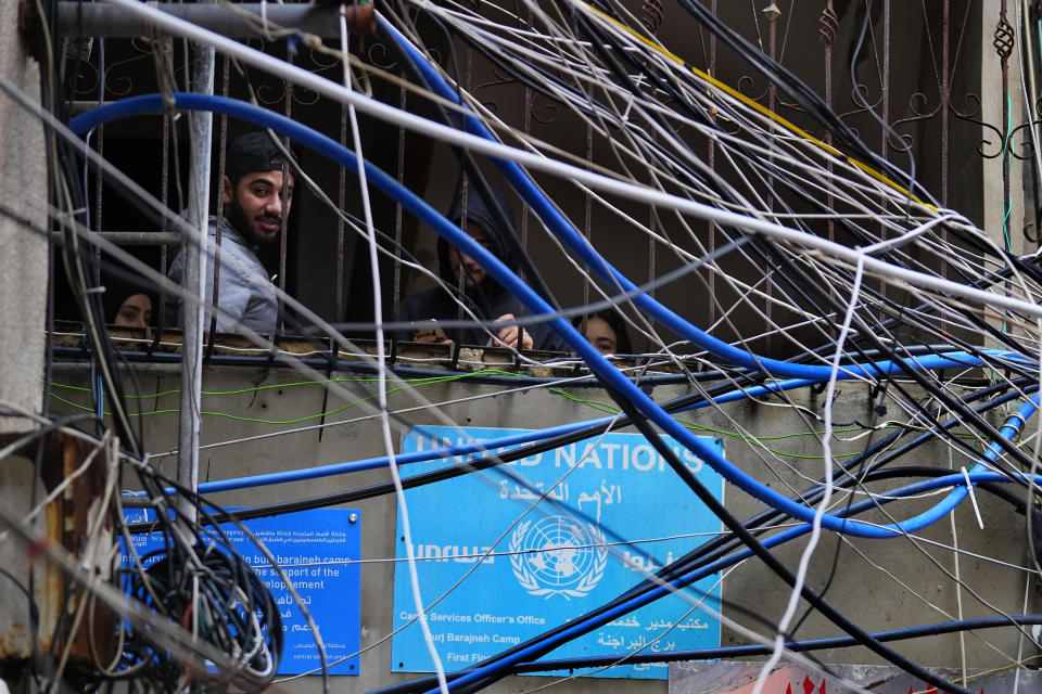 Palestinians look out through improvised electricity cables and water tubes at Bourj al-Barajneh Palestinian refugee camp, south of Beirut, Lebanon, Monday, Feb. 5, 2024. There are nearly 500,000 Palestinian refugees registered in Lebanon, although the actual number in the country is believed to be around 200,000, as many have emigrated but remain on UNRWA's roster. (AP Photo/Bilal Hussein)