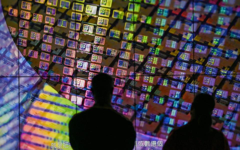 Visitors watch a wafer shown on screens at the TSMC Renovation Museum at the Hsinchu Science Park in Taiwan