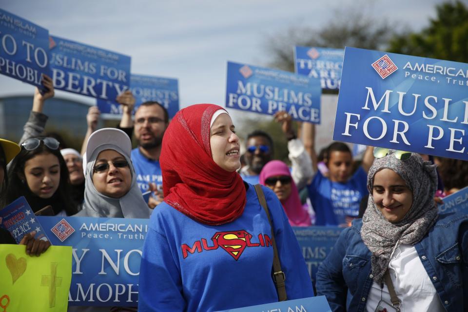 Protesters stand across the street from a Donald Trump rally holding signs for 