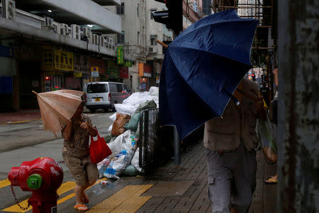 People brave strong winds on a street as Typhoon Haima approaches in Hong Kong, China . REUTERS/Bobby Yip