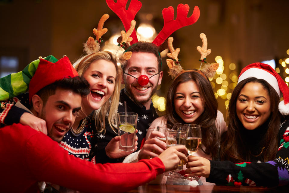 Group Of Friends Enjoying Christmas Drinks In Bar Smiling To Camera