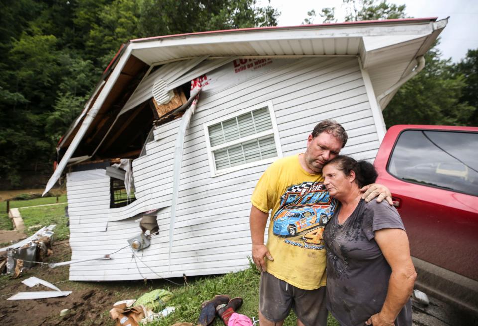 Reggie Ritchie comforts wife Della as they pause while clearing out their Fisty, Ky., home destroyed by the flooding from Troublesome Creek behind them. July 29, 2022